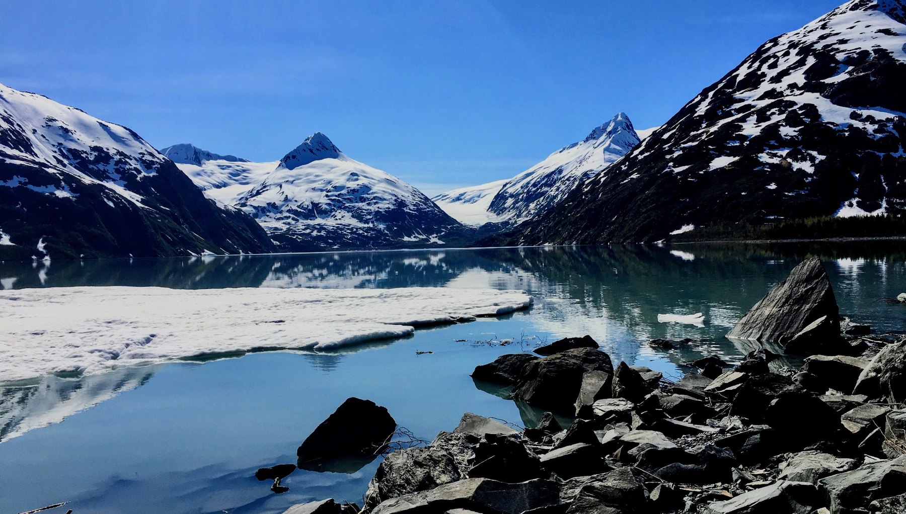Snowy mountains reflected in a still Alaskan lake