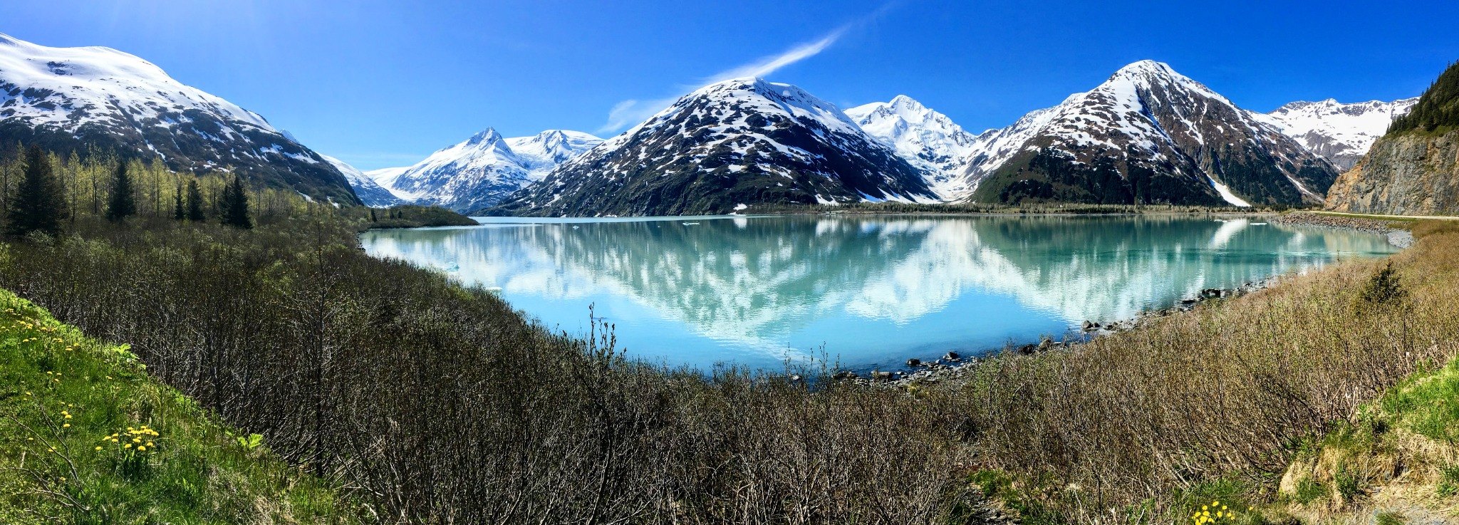 Wide panorama of snowy mountains reflected in turquoise water