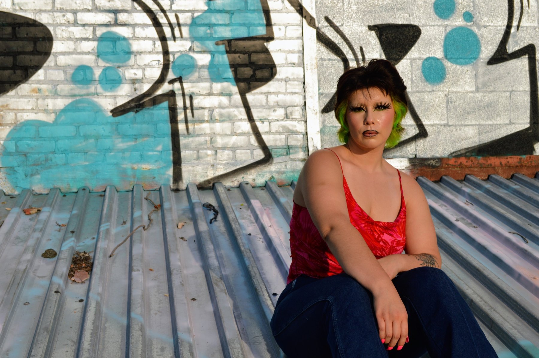 Green-haired portrait against a blue graffiti wall