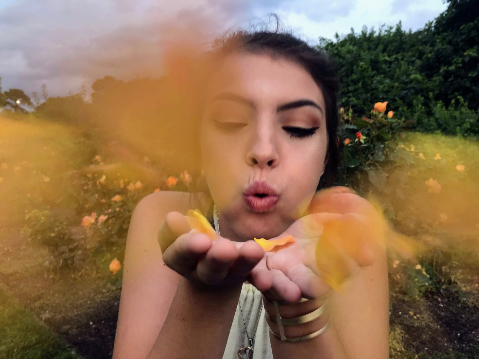 Person blowing yellow-orange flower petals toward the camera