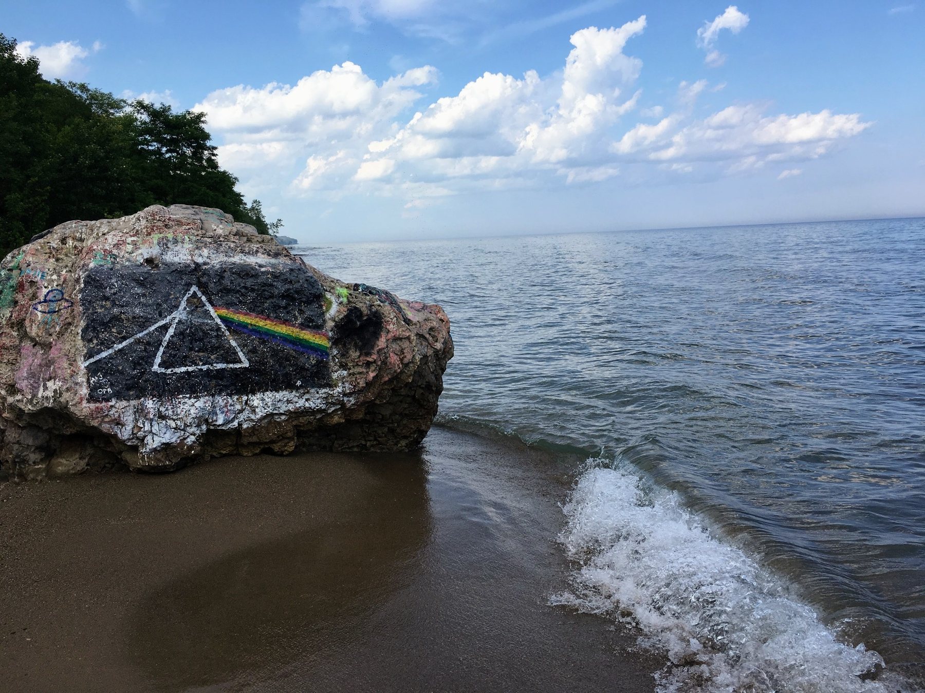 Rainbow prism painted on a lakeside rock beside open water