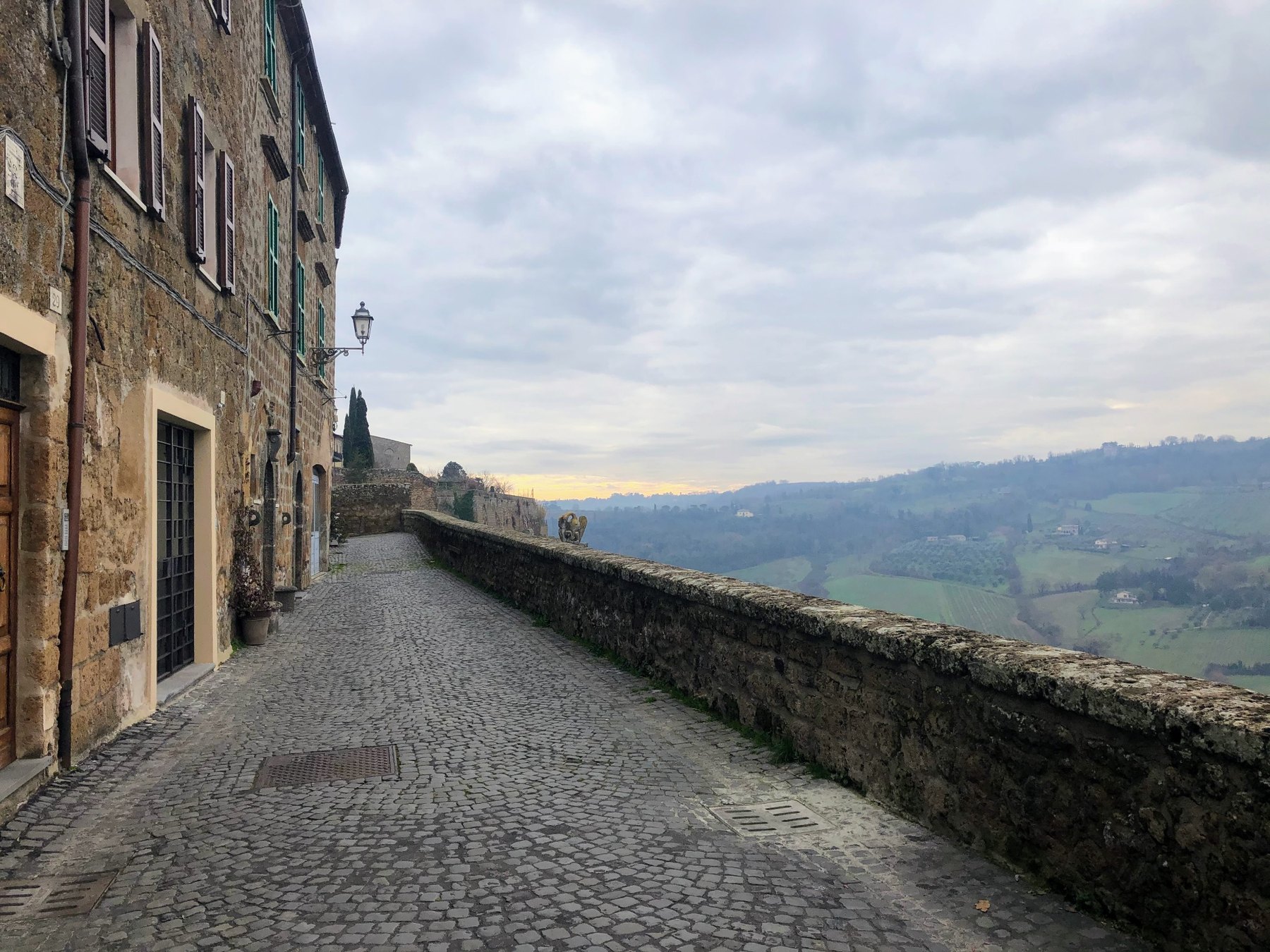 Stone street opening toward countryside and hills