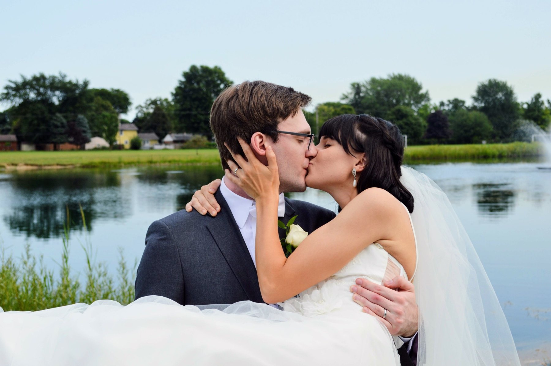 Wedding couple kissing beside the water