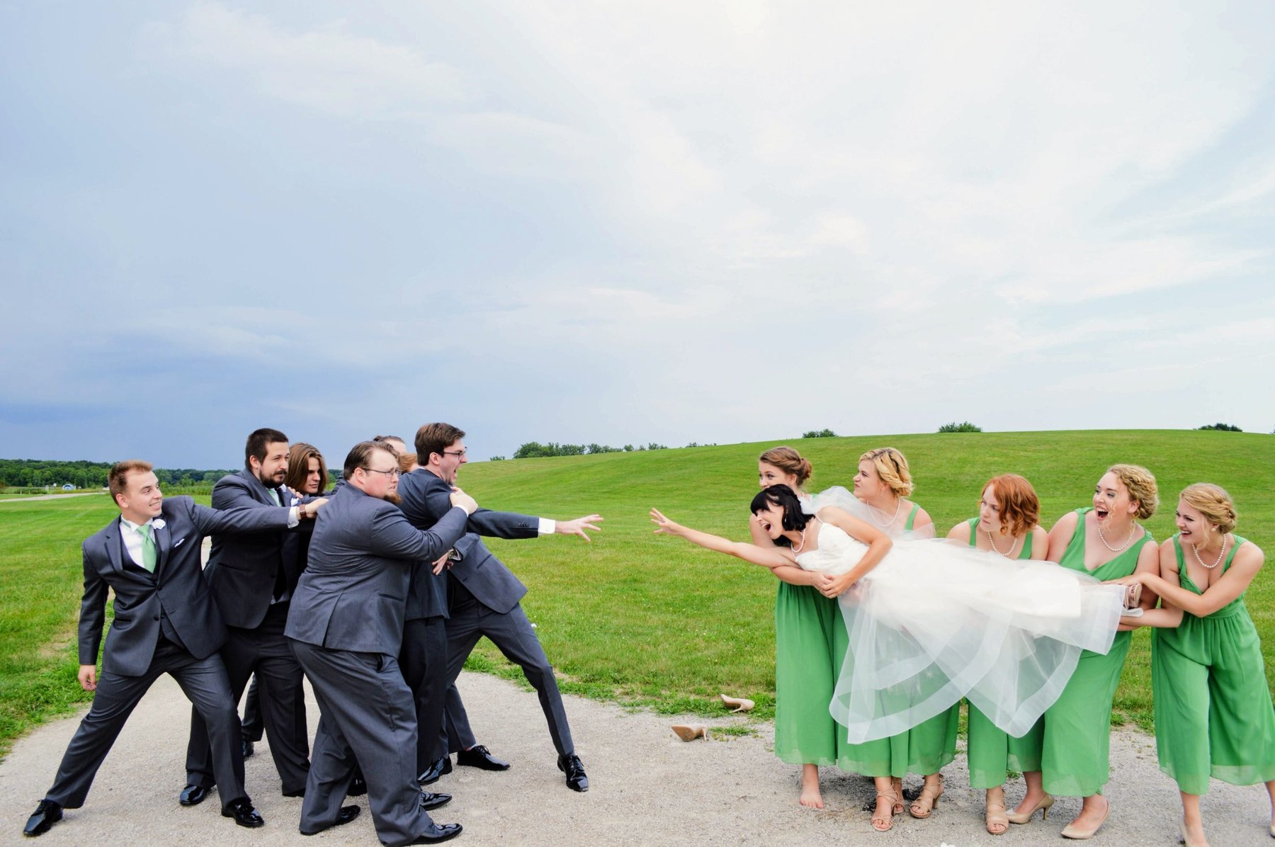 Wedding party in a playful tug-of-war moment